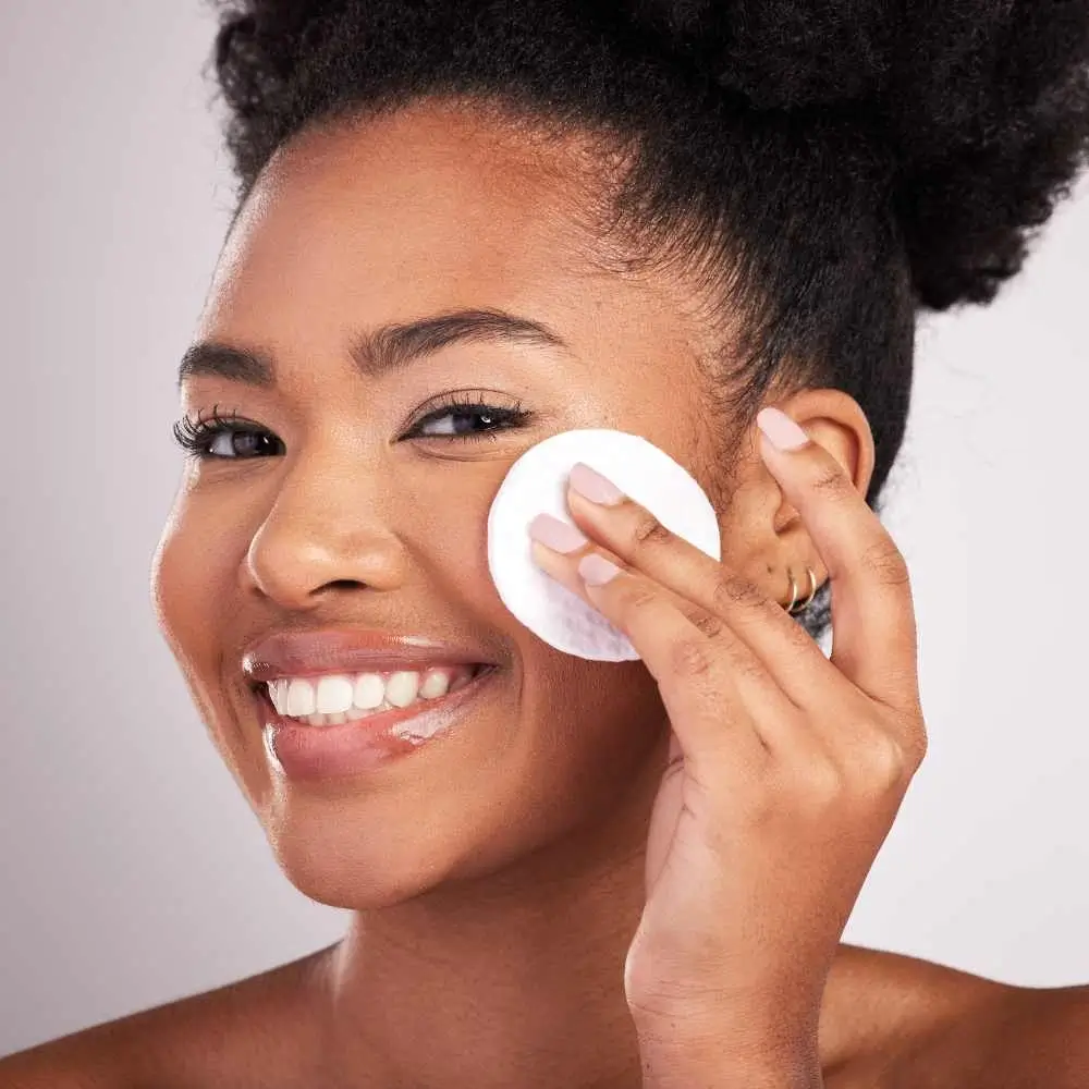 black woman removing her makeup using a cotton pad