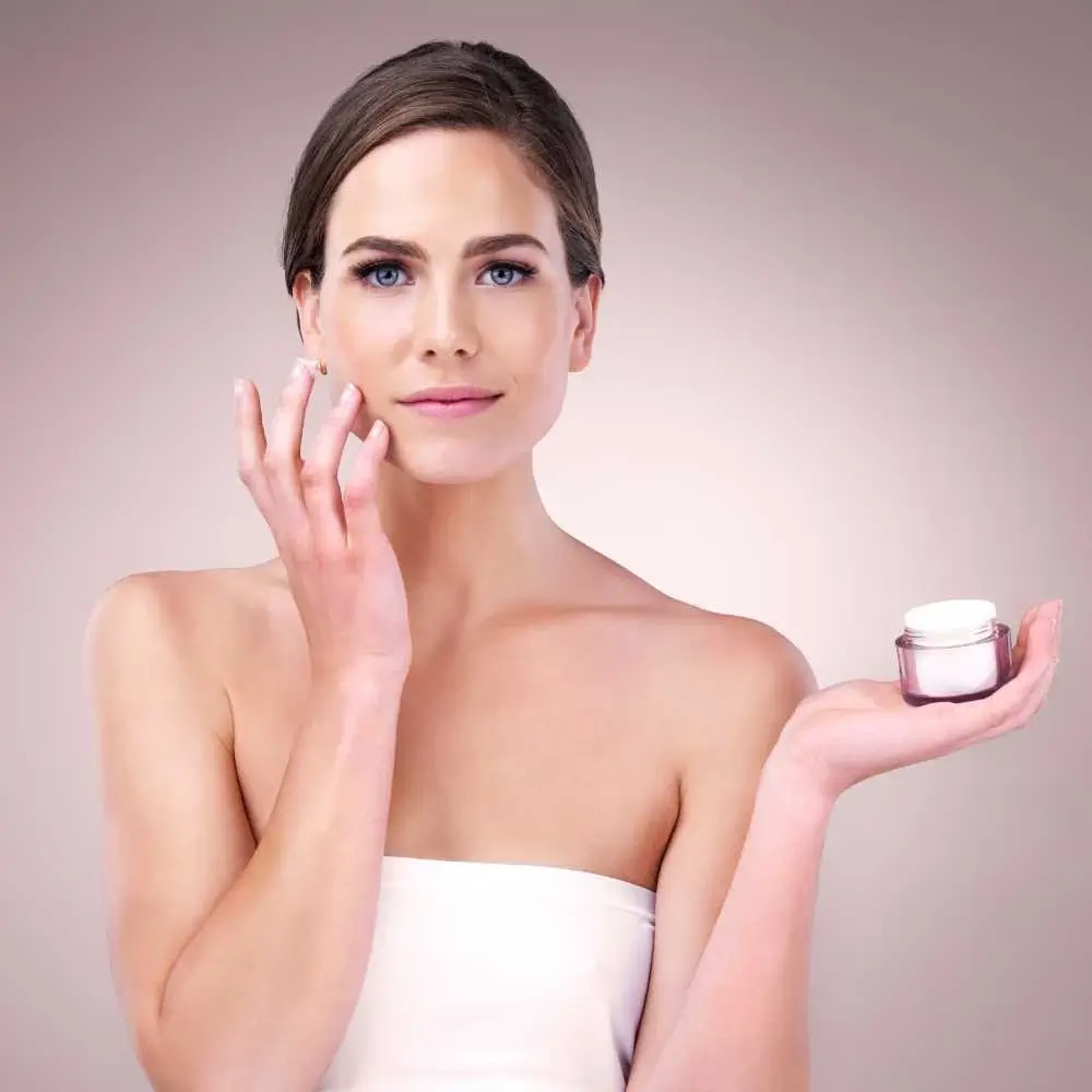 brunette woman applying moisturizer on her face