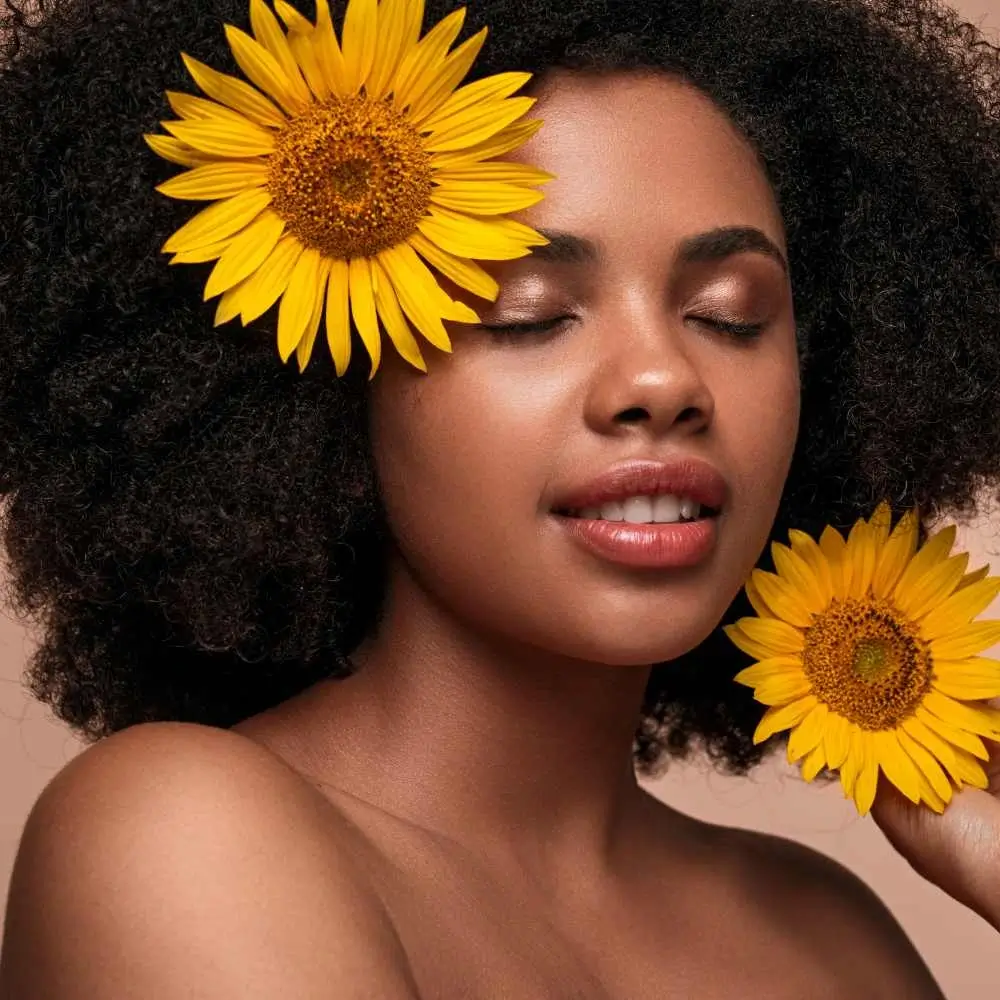closeup portrait of black woman with sunflower on her hair