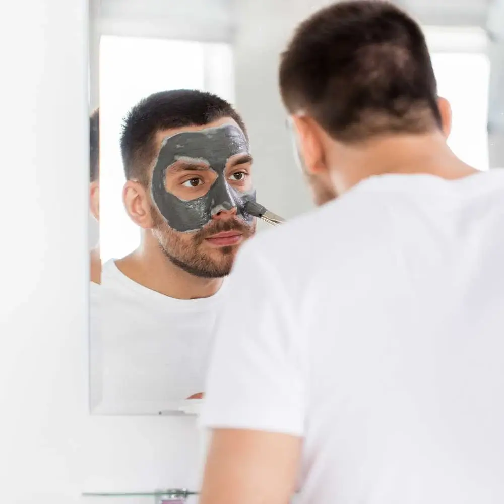 a man applying face mask in front of the mirror