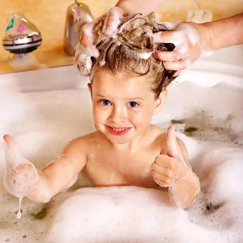 little kid taking a bath with shampoo on her hair