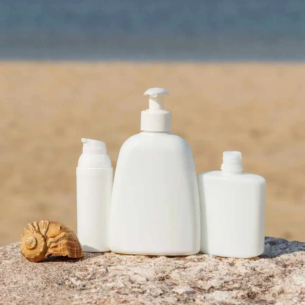 sunscreen products and a shell on the beach