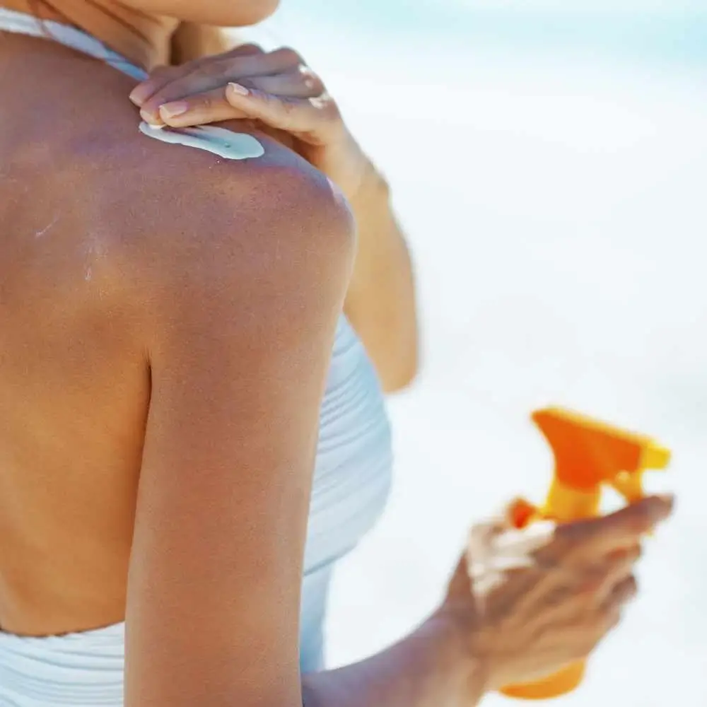 woman applying sunscreen on her right shoulder