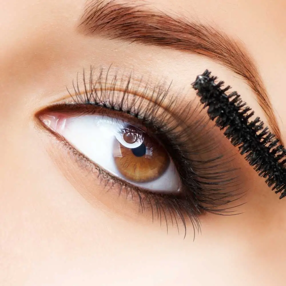 close-up shot of an eye with long lashes and mascara brush