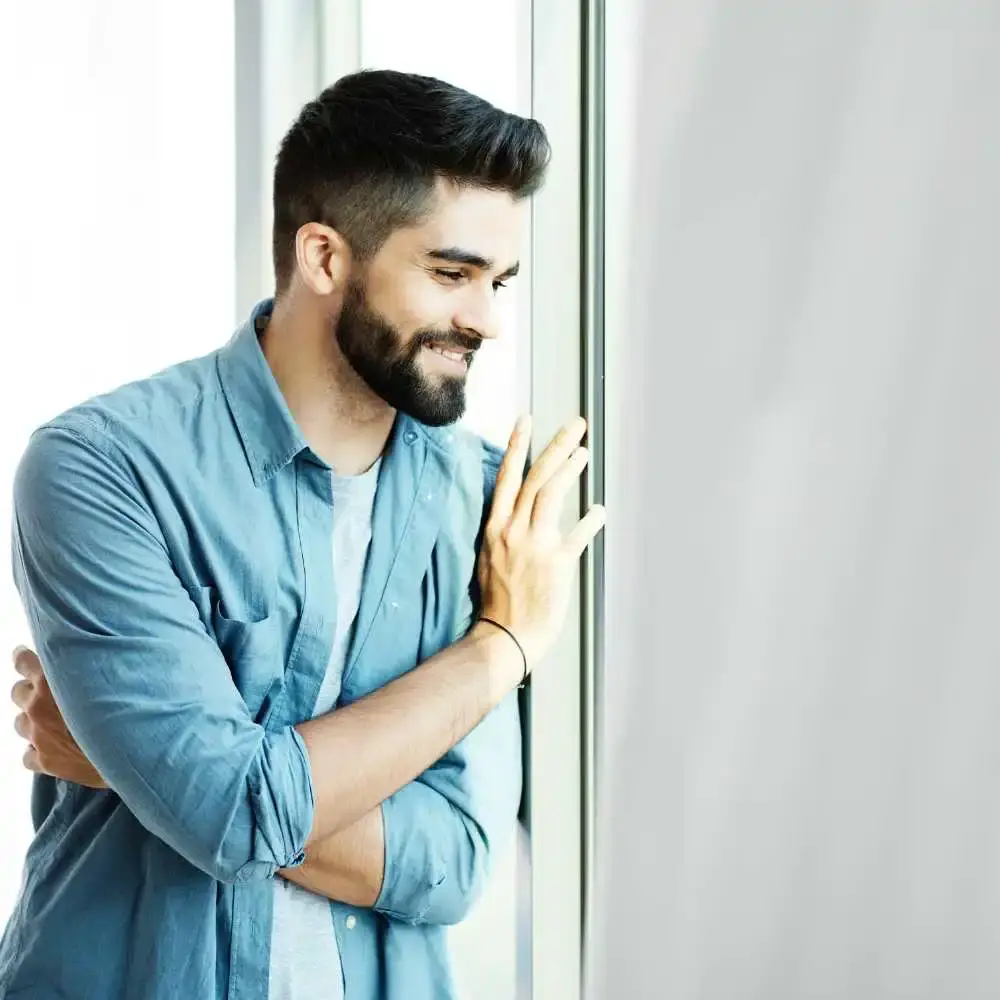 man with black beard smiling and standing by the door 