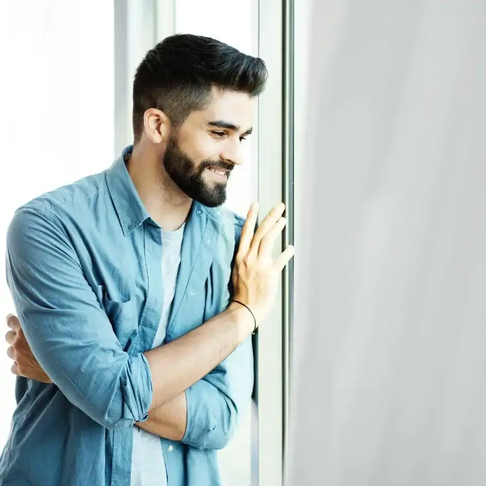 man with black beard smiling and standing by the door
