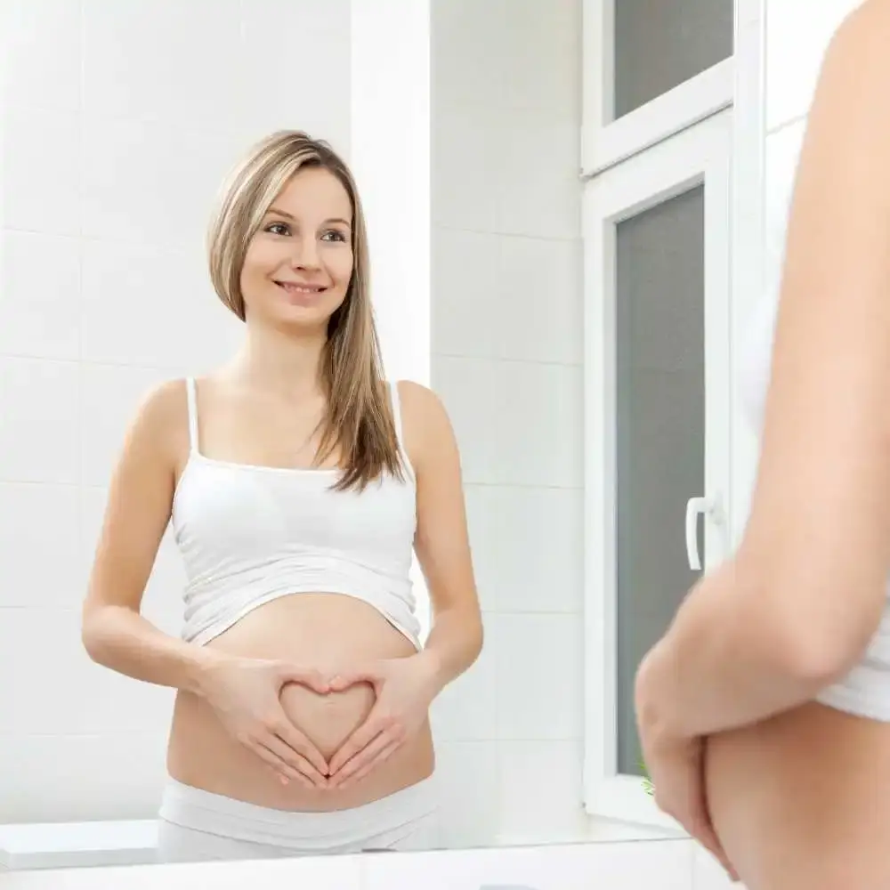 pregnant woman smiling in front of a mirror