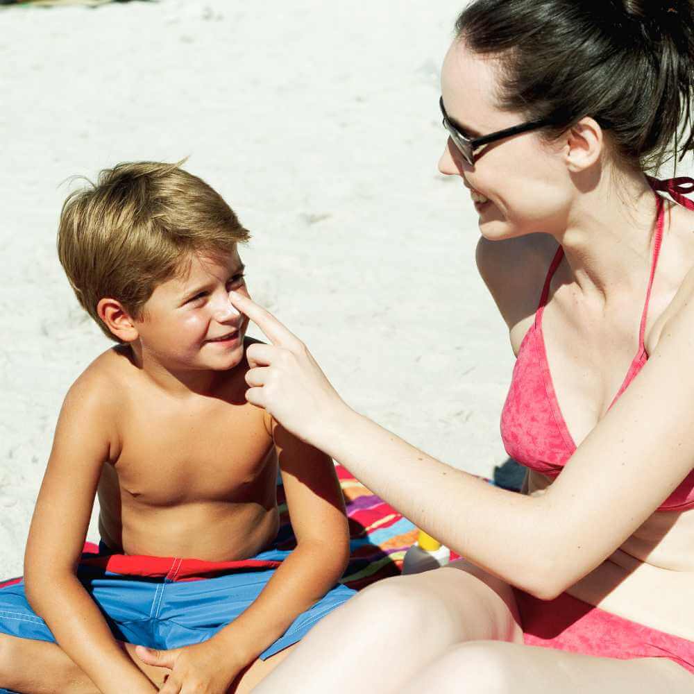 mother applying sunscreen on his son's face
