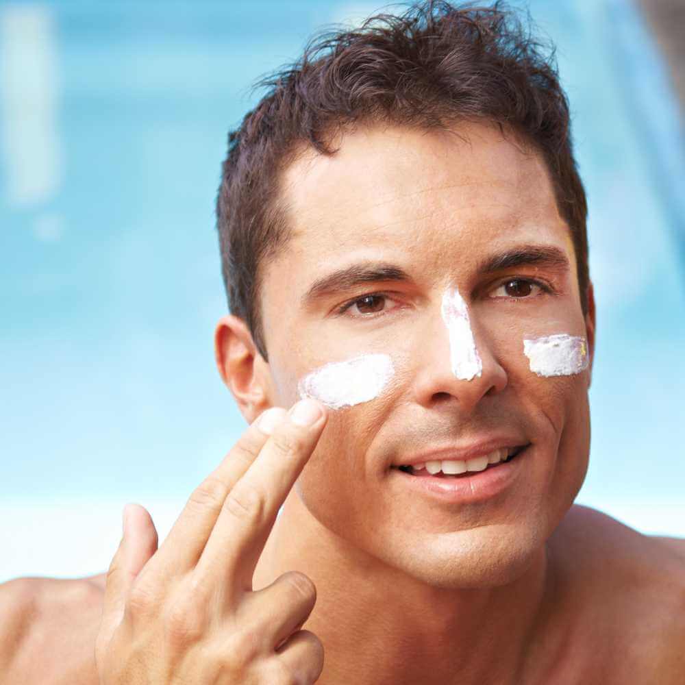 man applying sunscreen on his face