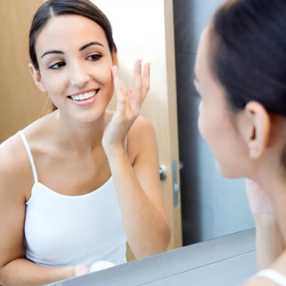 woman looking at her face in the mirror