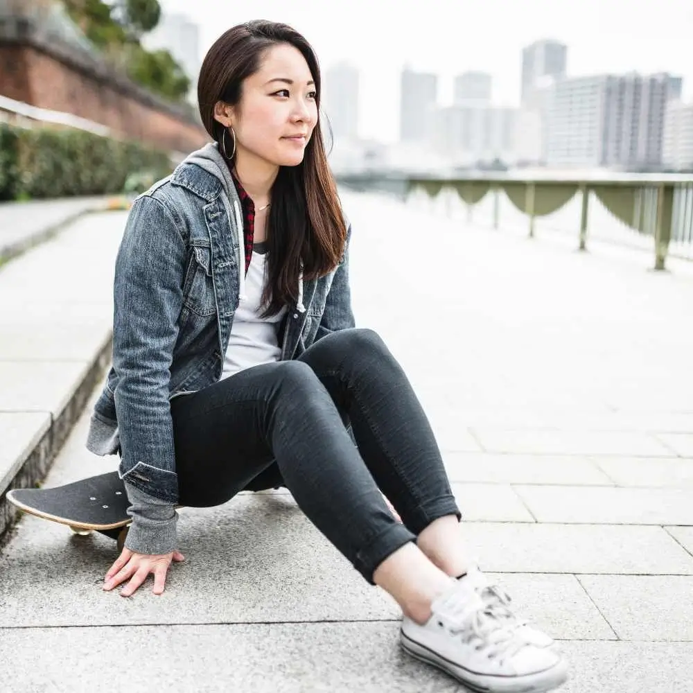 Japanese woman sitting on her skateboard