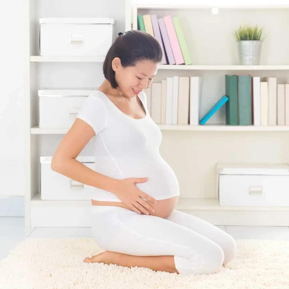 pregnant woman sitting on the carpet holding her belly