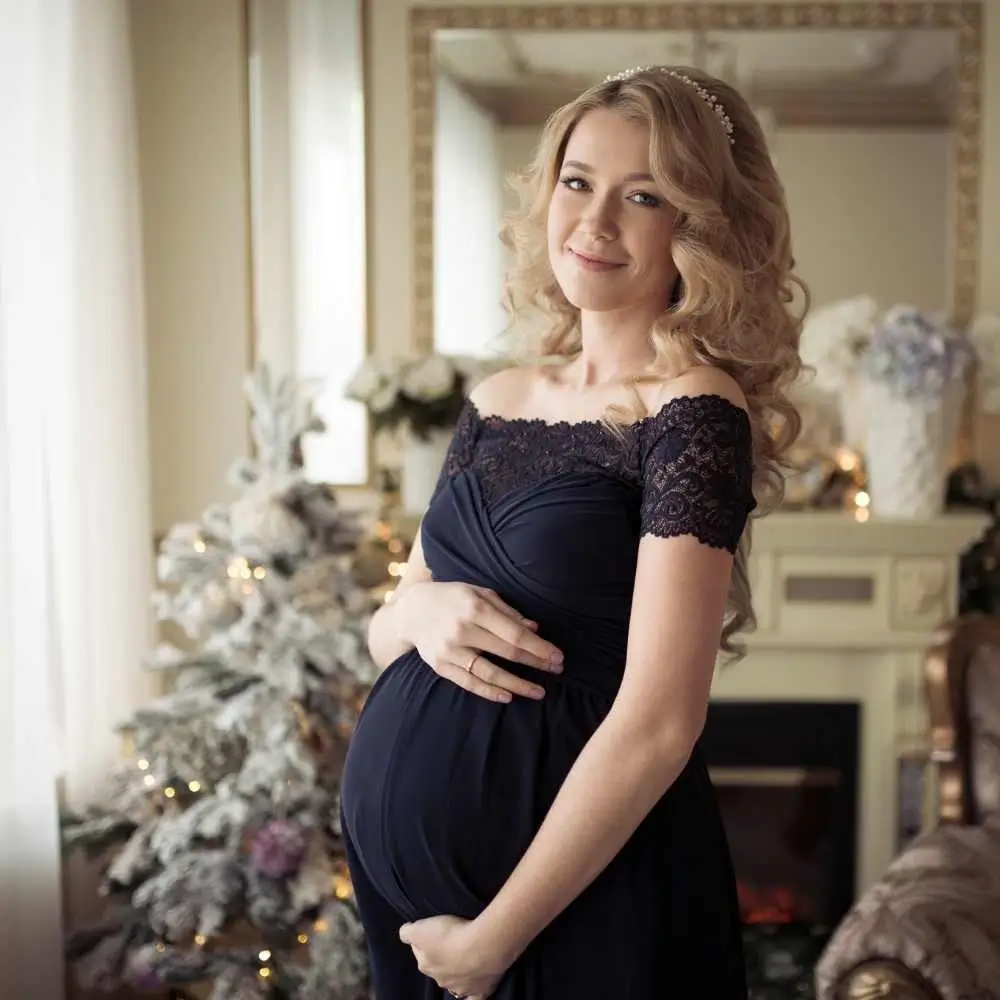 smiling pregnant woman wearing a black dress and holding her belly