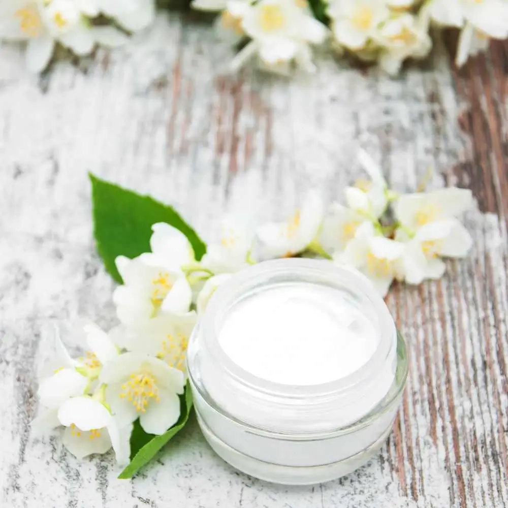 vitamin C moisturizer in a glass container adorned with white flowers