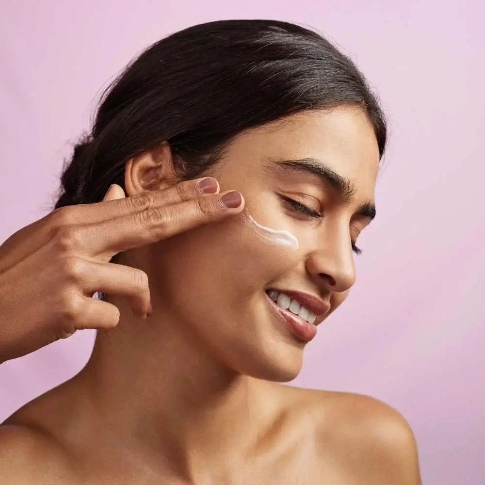 closeup portrait of a woman applying moisturizer on her face