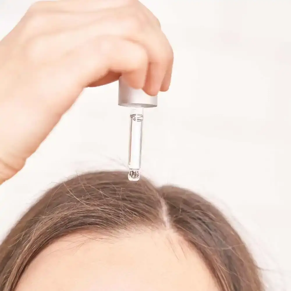 closeup of a woman's head while applying hair oil