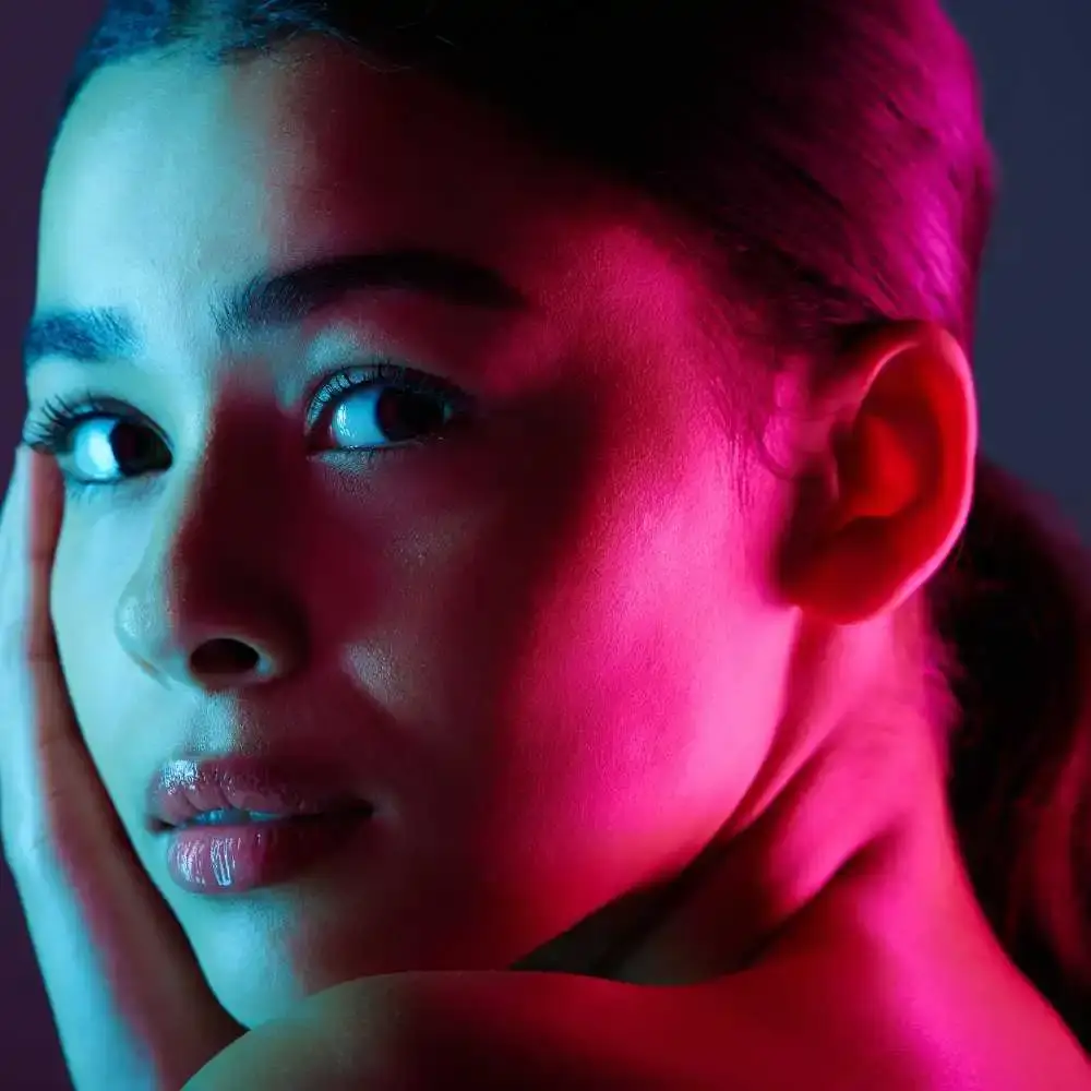 closeup side view portrait of a woman with pink neon light reflected on her face