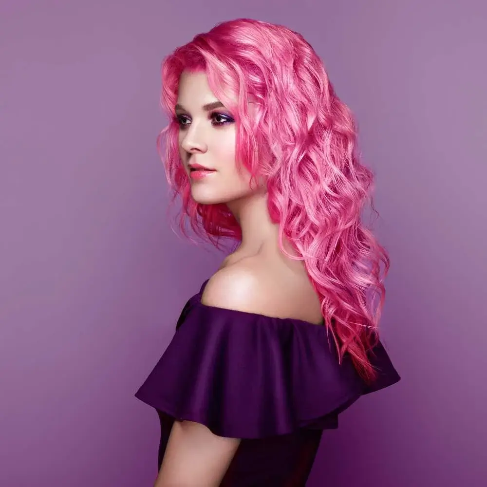 young woman wearing violet dress with curly bright pink hair