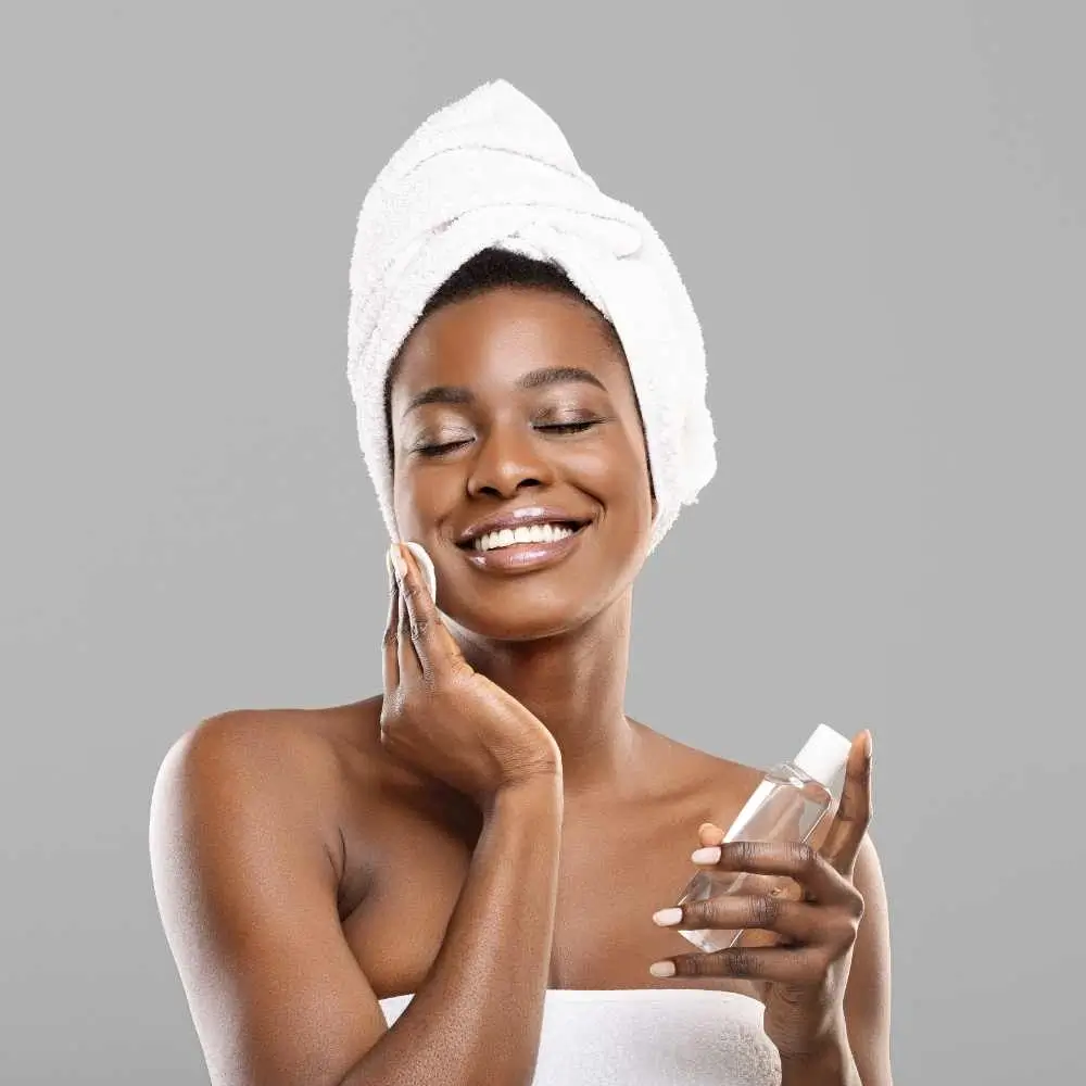 woman applying toner with cotton pad on her face