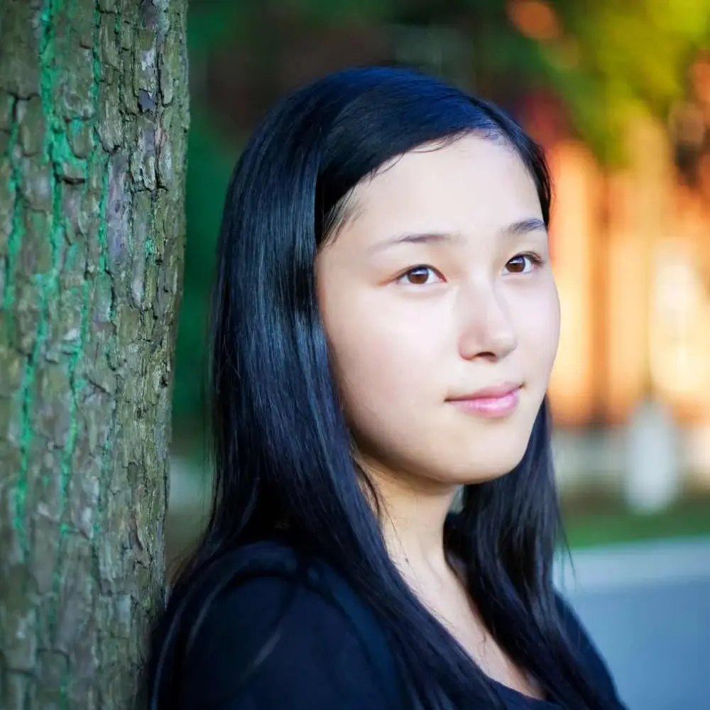 closeup portrait of a young asian female standing by the tree