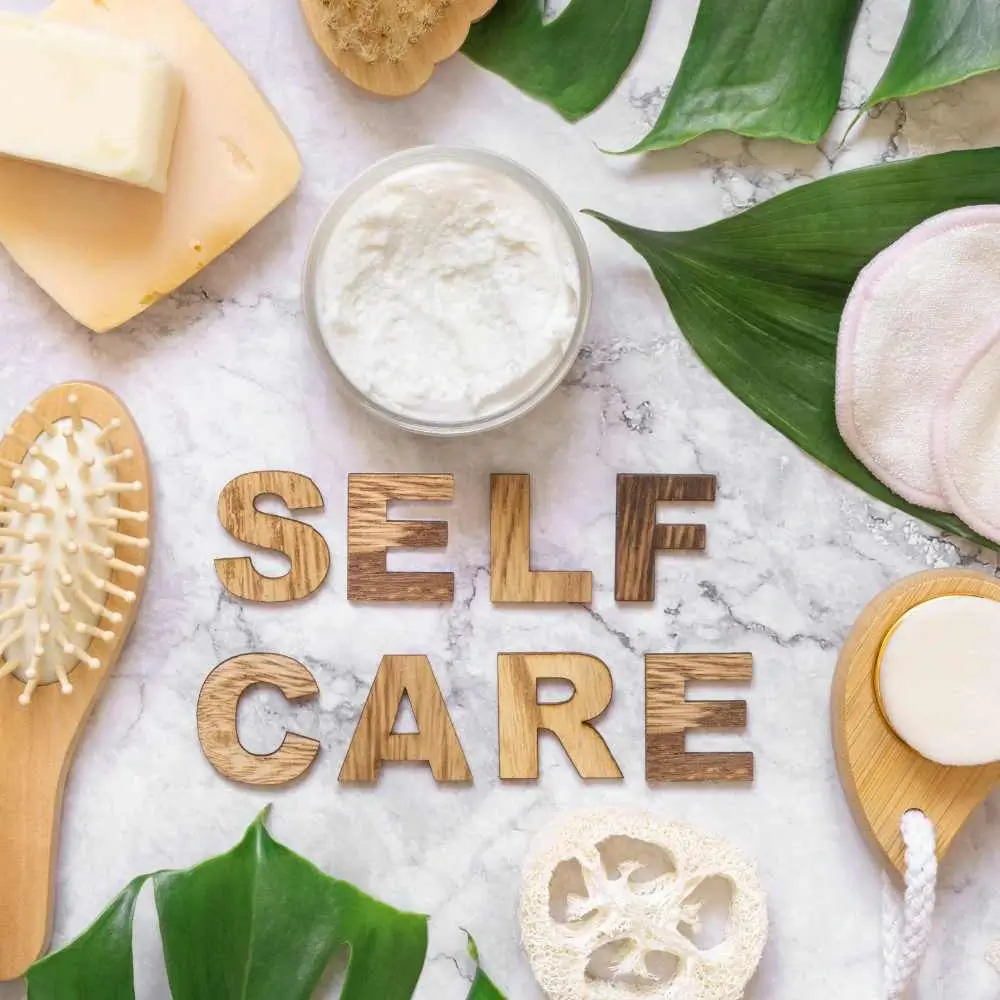 bath essentials and green leaves with self-care text in the middle