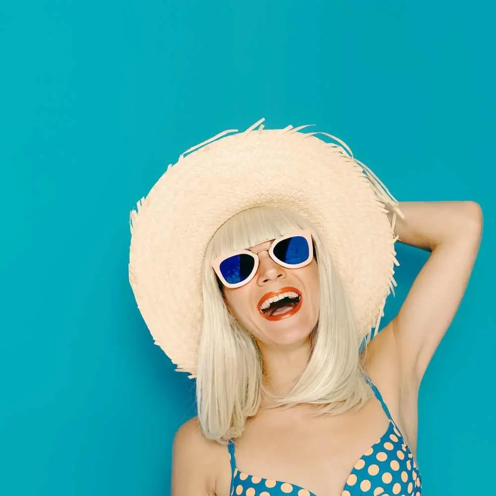 portrait of a young woman laughing and wearing a beach hat
