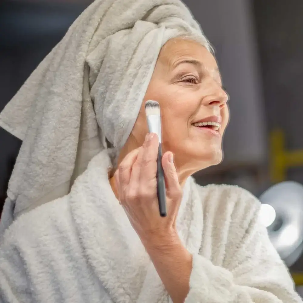 Mature woman applying the best setting powder with a brush