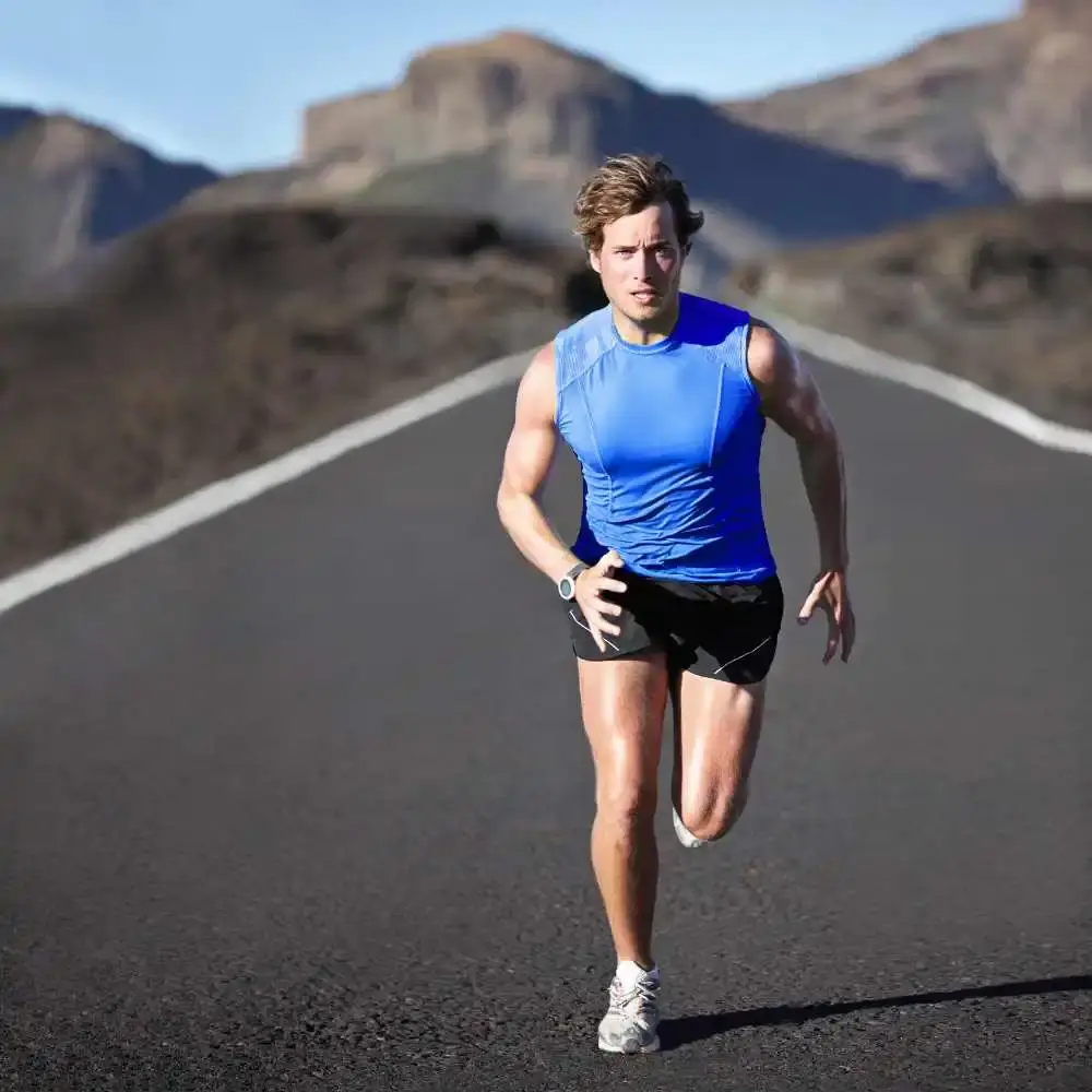 an athletic man running in the middle of the road wearing blue shirt and black shorts