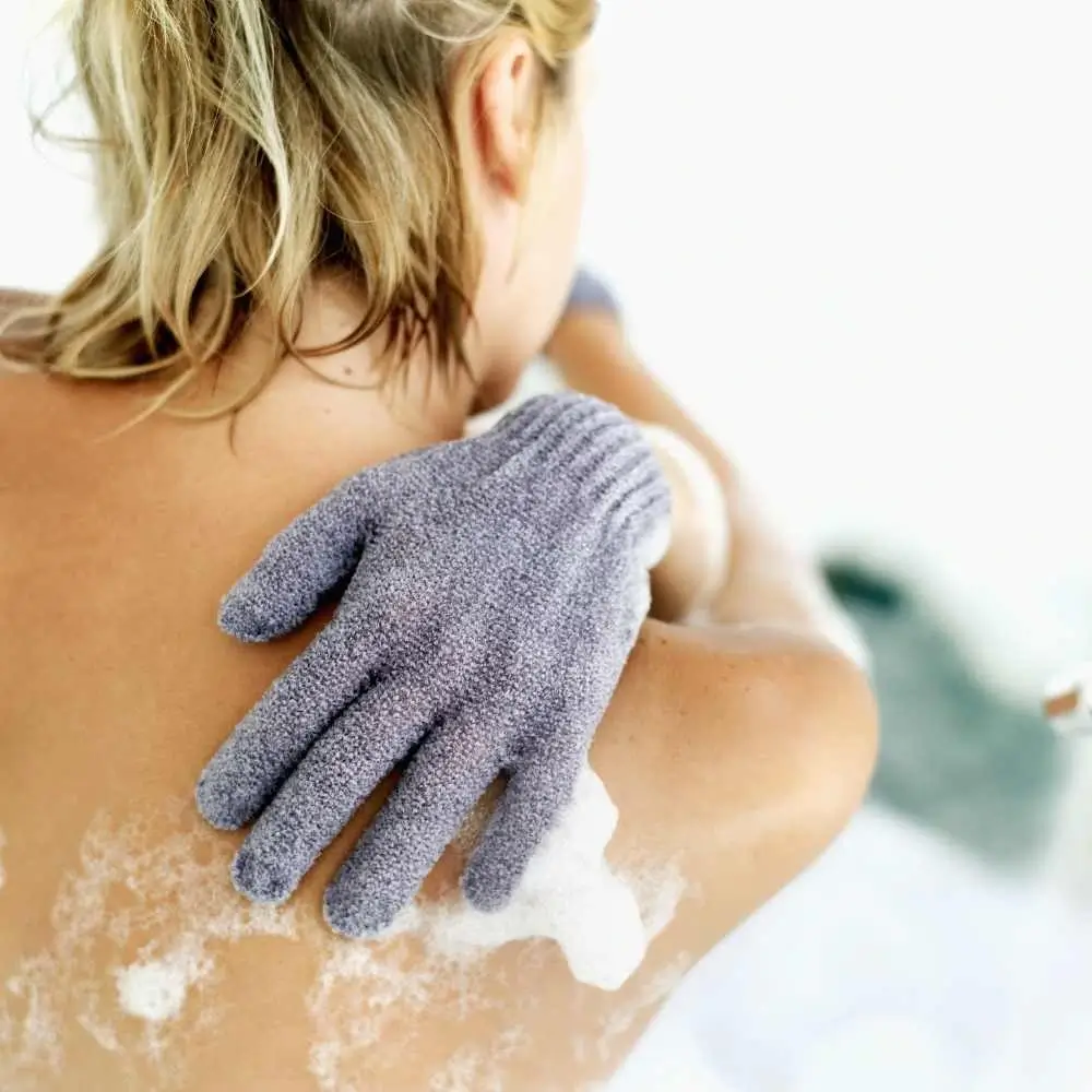 young woman scrubbing her back using glove scrubber
