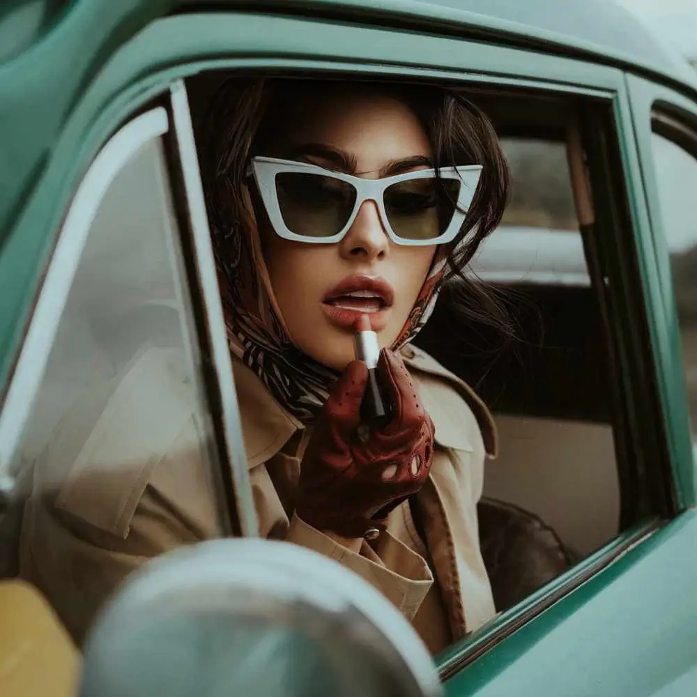 woman applying lipstick inside the car