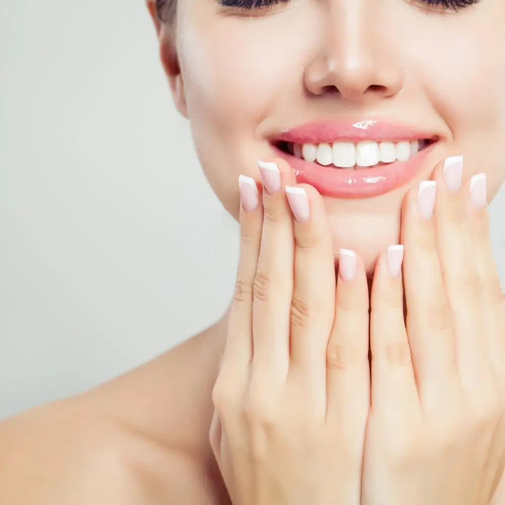 cropped close-up shot of a woman smiling and wearing clear lip gloss