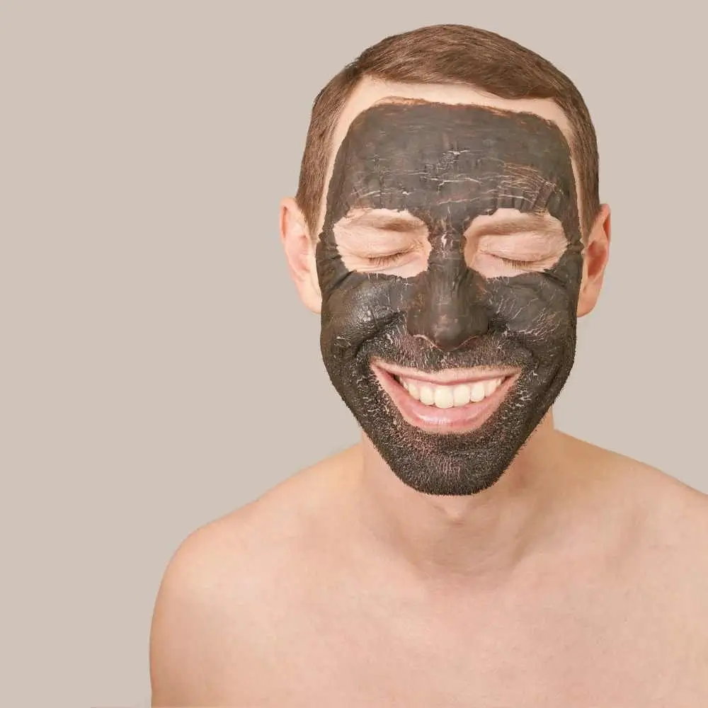 man with a black clay mask on his face