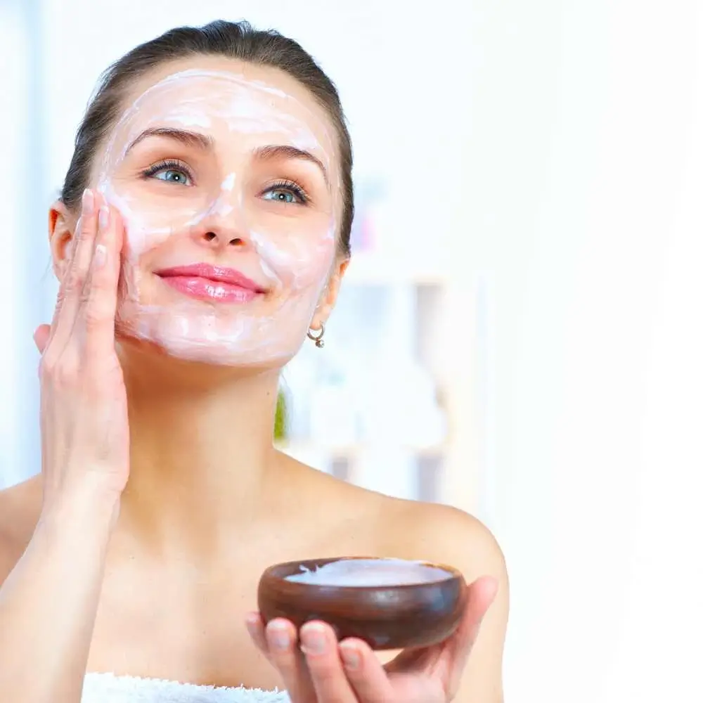 a smiling woman applying the face mask