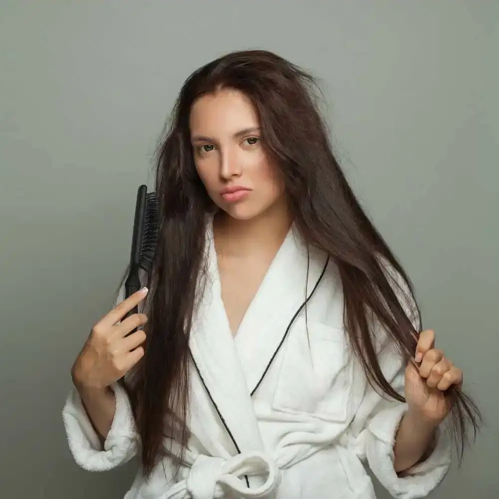 frowning woman with long tangled hair holding a hairbrush