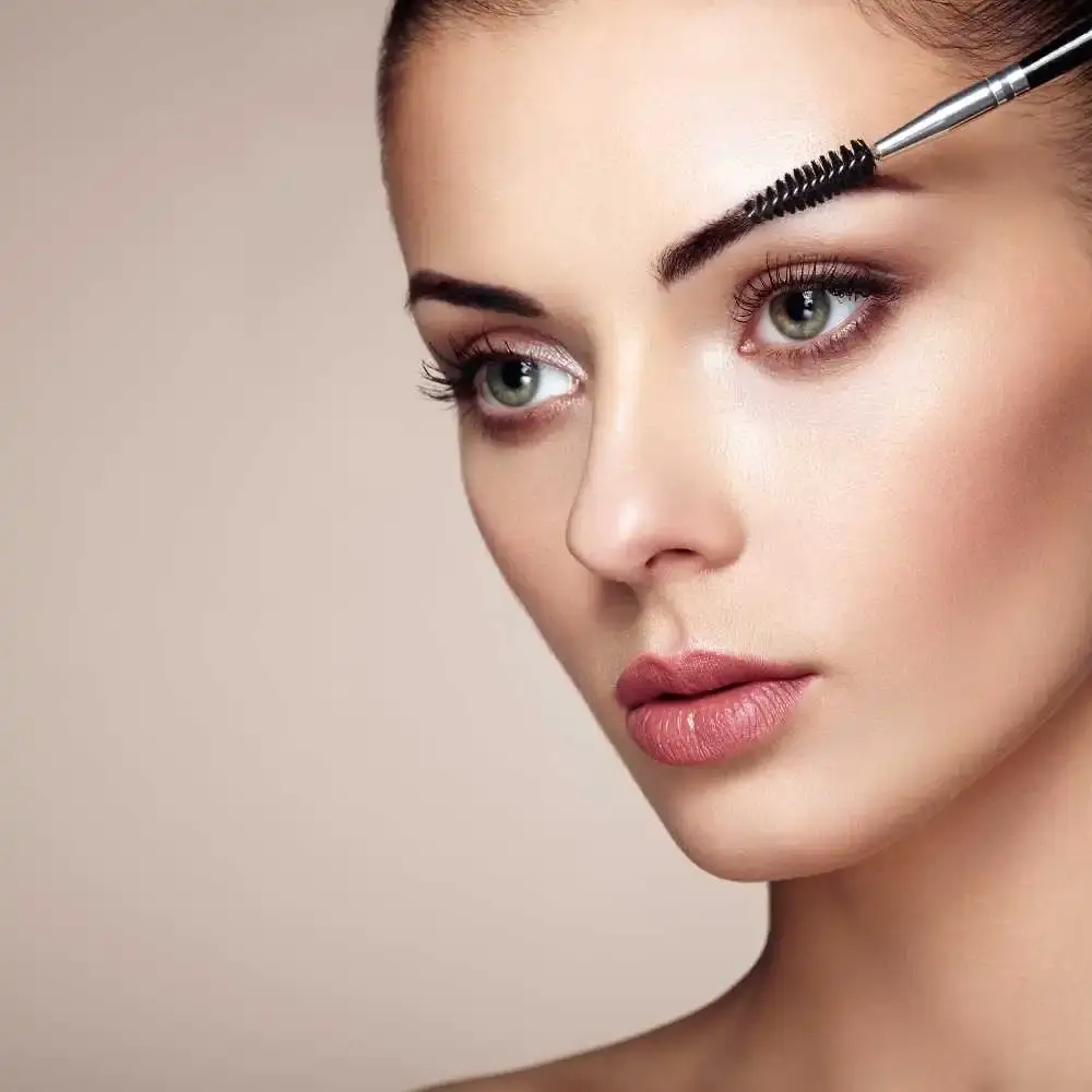 closeup view of a young woman's face using an eyebrow brush