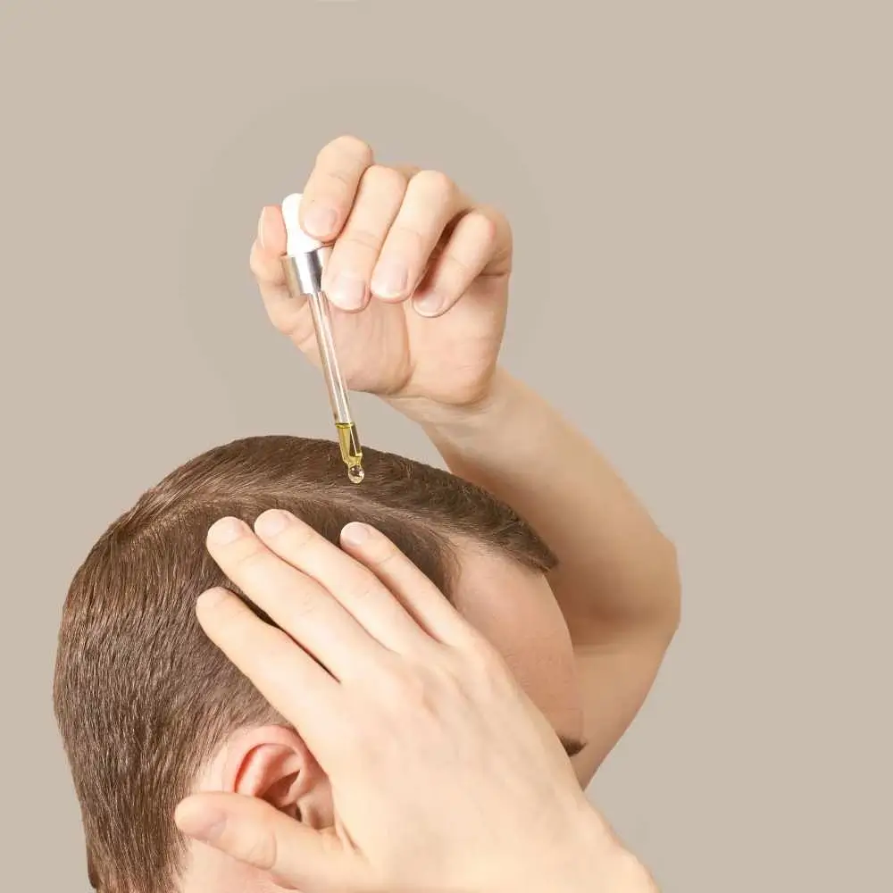 man applying coconut oil on his scalp