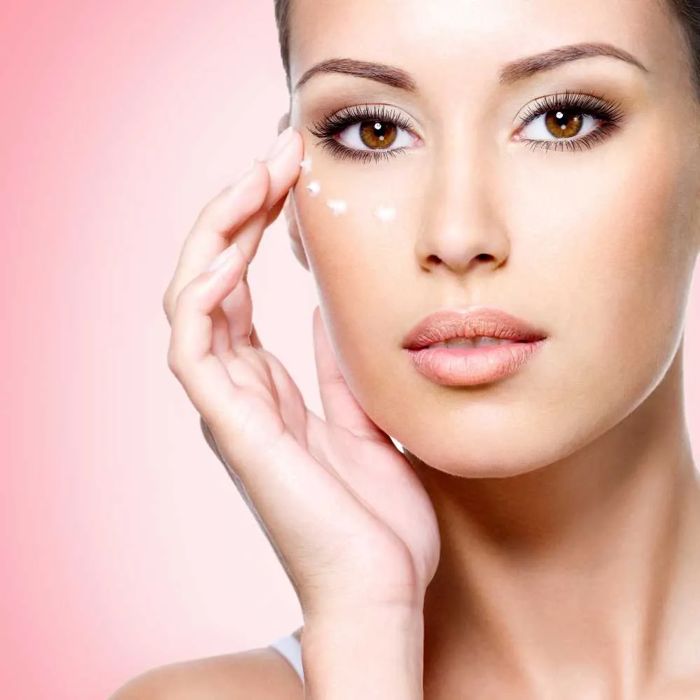 closeup portrait of a woman applying eye cream under her eyes