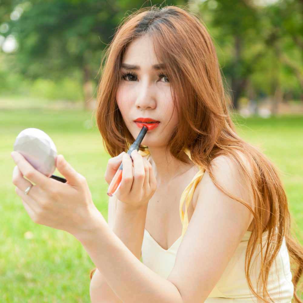 asian woman applying a red lipstick