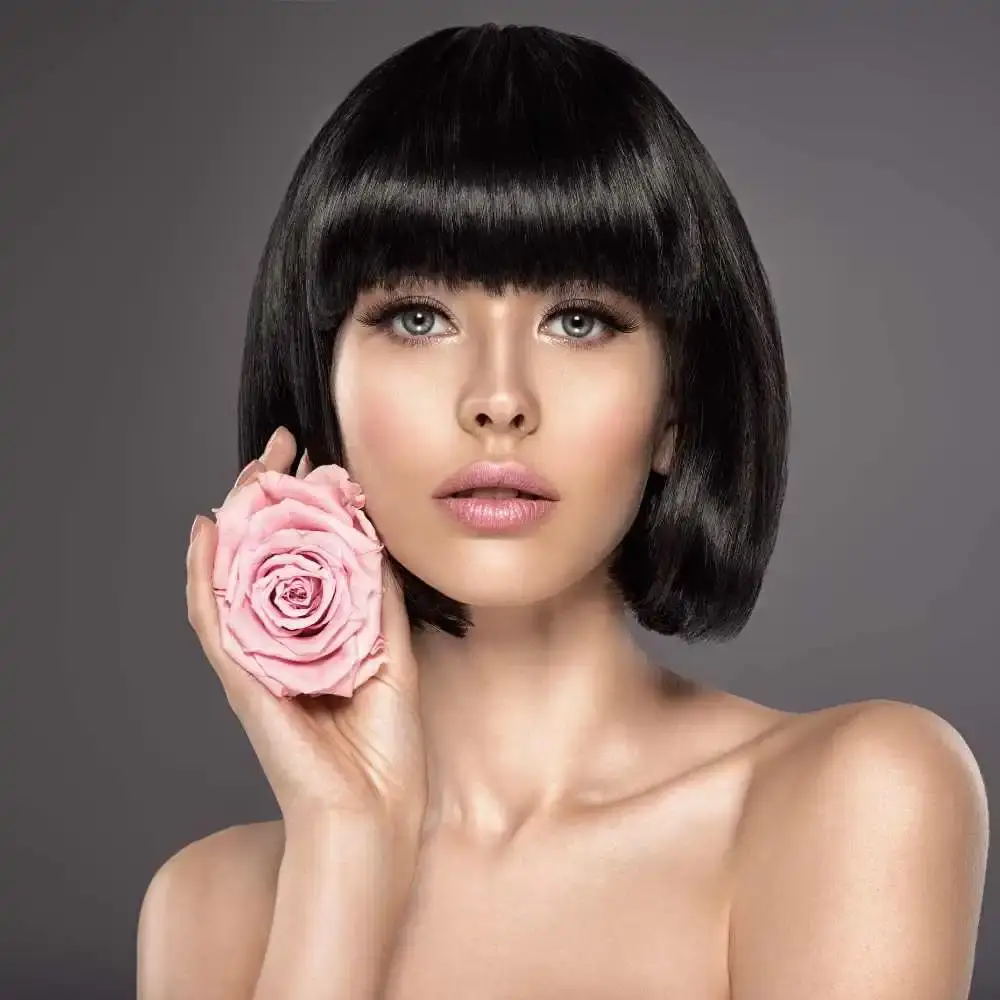 woman with short black hair holding a light pink rose