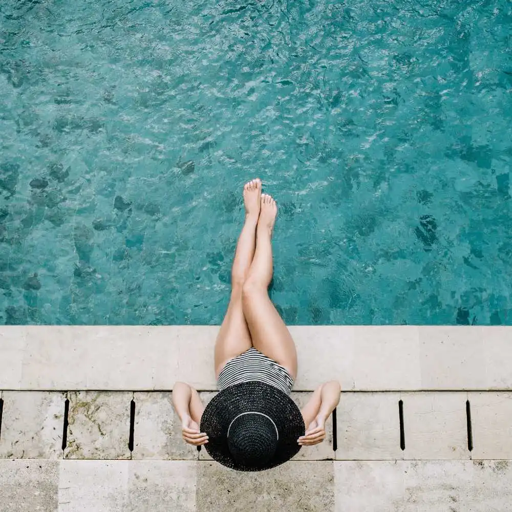 woman wearing a black hat and sitting by the pool