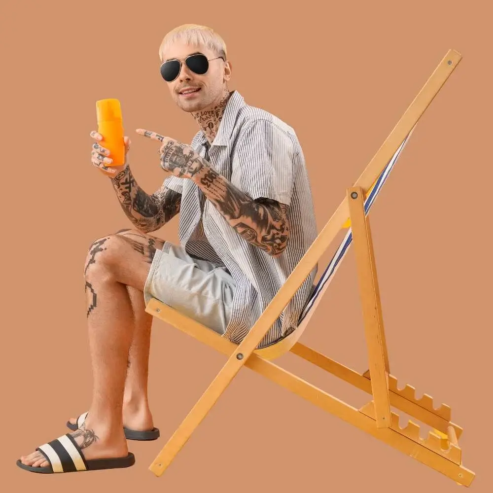 man with tattoo holding sunscreen bottle