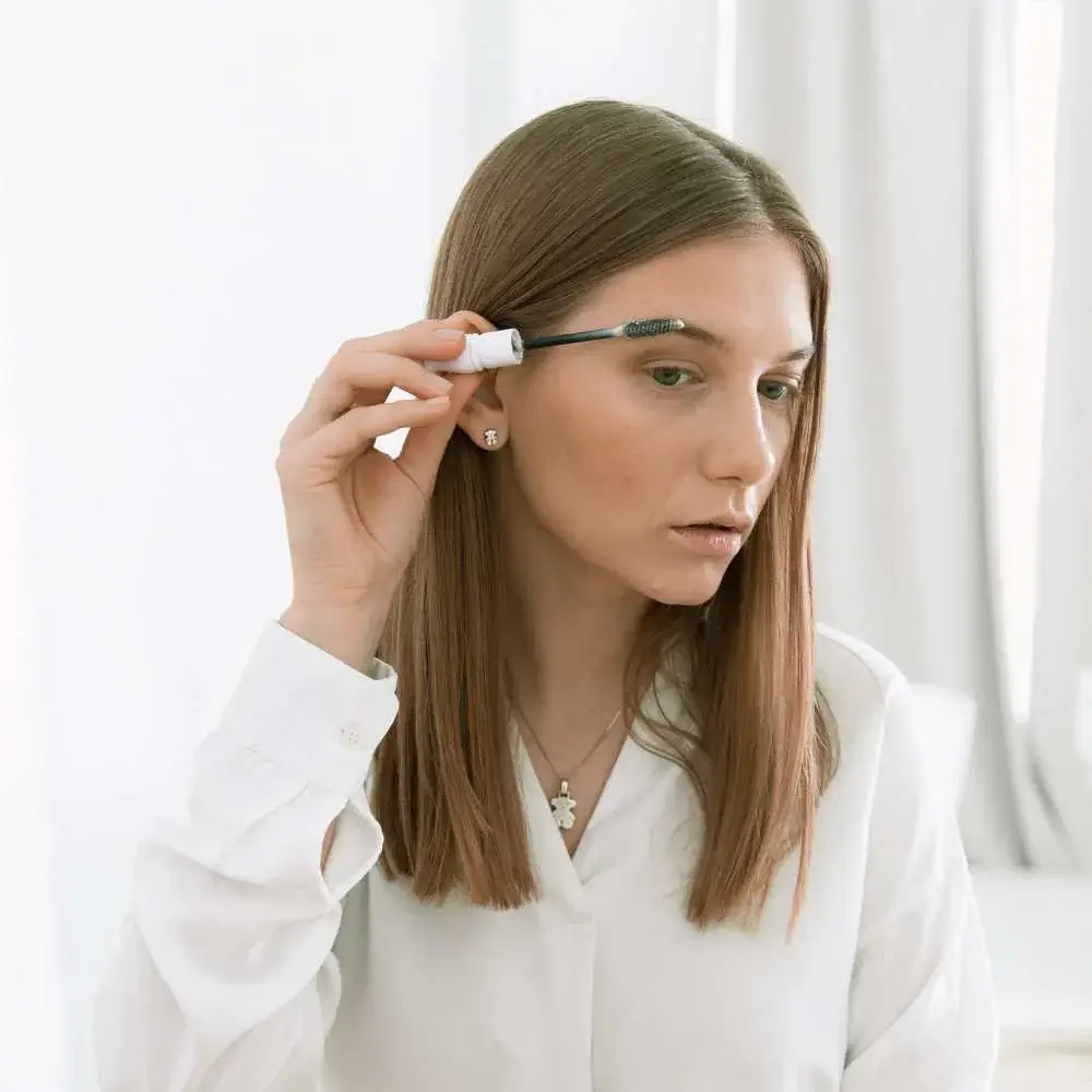 Close-up of a person applying the best clear eyebrow gel