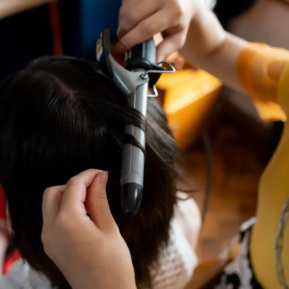 Person using top-rated curling iron for delicate fine hair