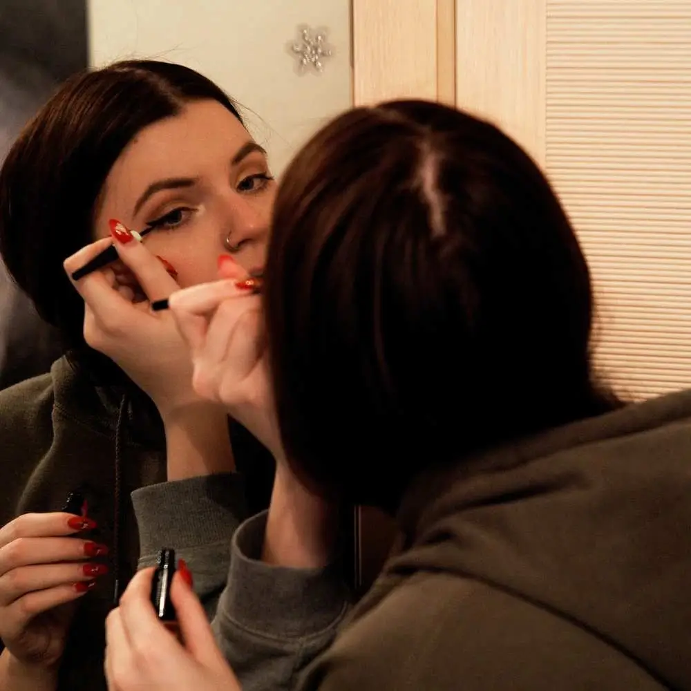 applying eyeliner in front of mirror