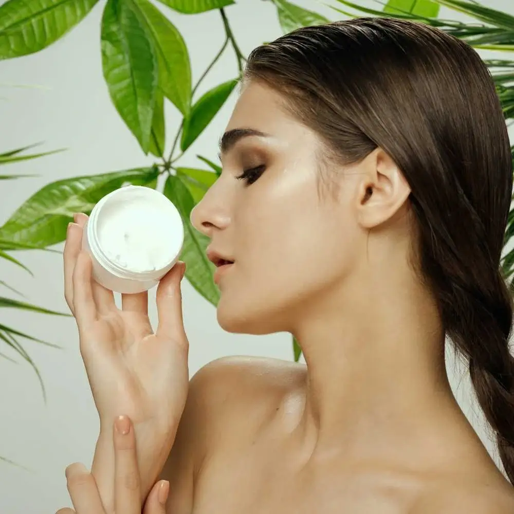 portrait side view of a woman holding an eye cream