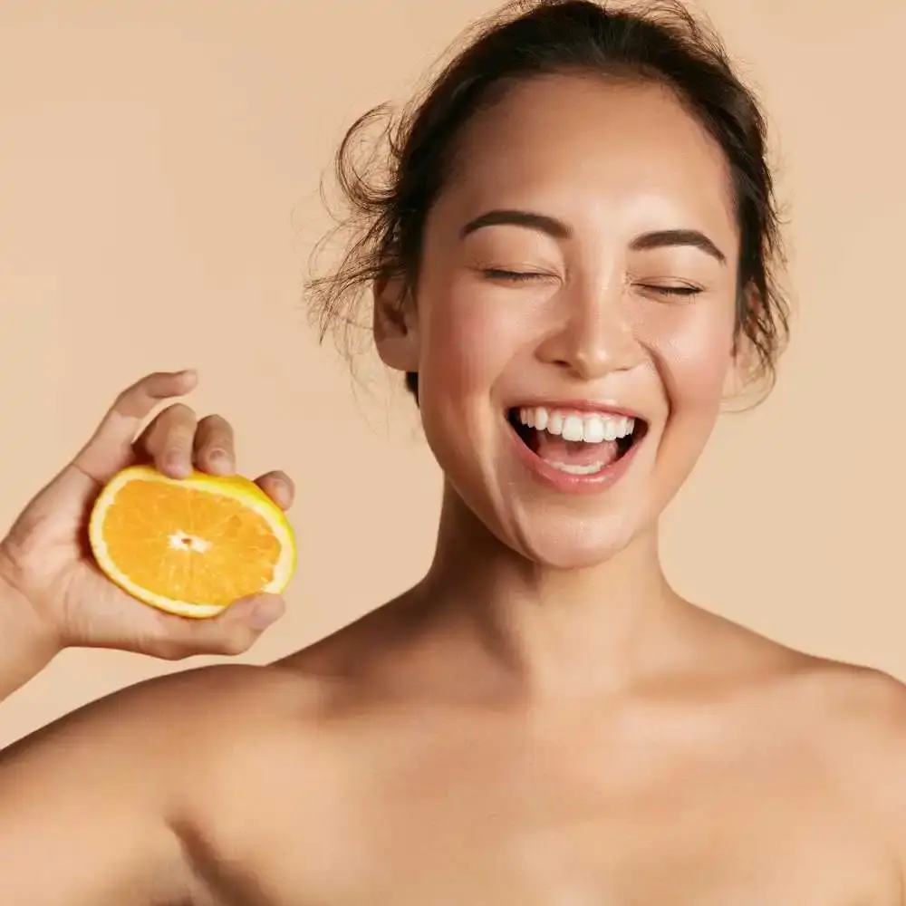 portrait of a woman with clear skin smiling and holding a sliced lemon