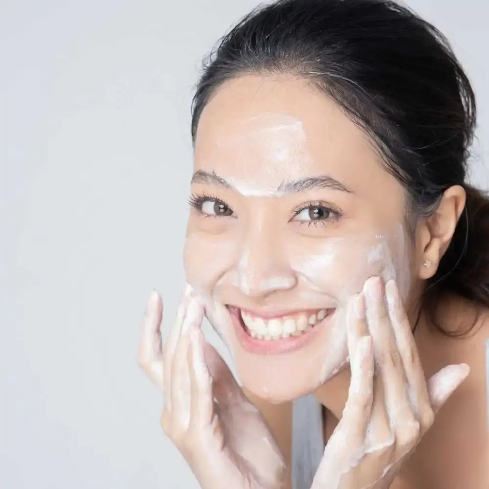 portrait of a smiling Asian woman washing her face