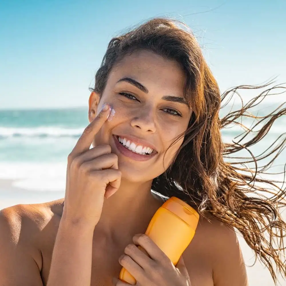 closeup portrait of a woman applying sunscreen on the beach