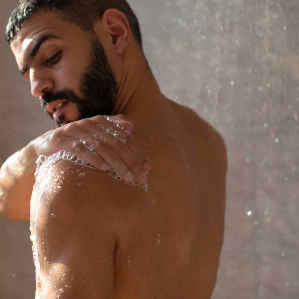 man taking a shower and washing his body