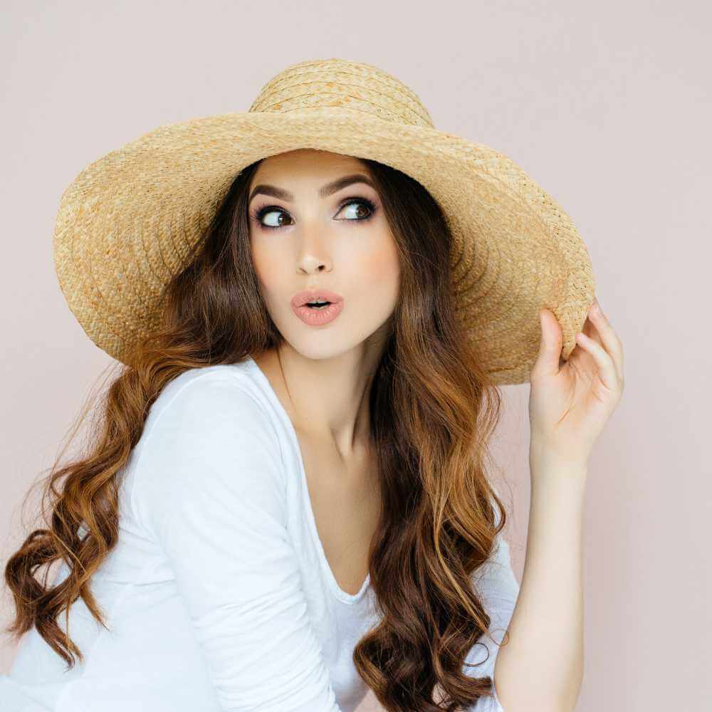 beautiful woman with healthy glowing skin wearing a beach hat